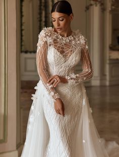 a woman in a white wedding dress with long sleeves