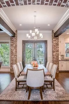 a dining room table with white chairs and a chandelier hanging from the ceiling