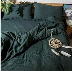 an unmade bed with green linens and feathers on the comforter, next to a potted plant