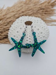 Add a touch of the ocean to your outfit with these stunning starfish earrings! These lightweight earrings are perfect for summer and will make you feel like you're under the sea, wherever you go. The sparkly glitter adds a touch of glamour to these tropical earrings, making them the perfect beach jewelry accessory. These shell earrings are a lovely gift for her, ideal for anyone who loves coastal jewelry and all things beach-related. Embrace the summer vibes with these beautiful ocean earrings t Nickel-free Starfish Earrings Ocean-inspired, Handmade Ocean-inspired Star Earrings, Ocean-inspired Star Earrings For The Beach, Ocean-inspired Star Earrings For Beach, Handmade Starfish Earrings For Beach, Ocean-inspired Starfish Charm Earrings, Ocean-inspired Drop Earrings With Starfish Charm, Star-shaped Ocean-inspired Earrings For Beach, Starfish Charm Earrings Gift