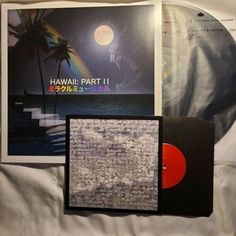 an image of a record and album on a bed with white sheets, palm trees and the moon in the background