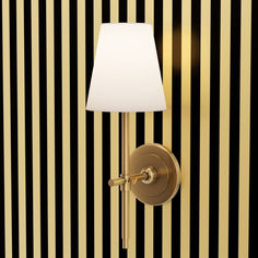 a lamp on a wall next to a black and white striped wallpaper with gold trim