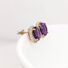 These stud earrings feature a pair of lovely purple natural, earth mined oval Amethyst in solid 14k gold with a natural diamond halo. These earrings can be a beautiful february birthstone gift for your loved ones! These earrings are made with solid 14k Gold and natural earth mined SI / G-H Diamonds. As listed, these earrings are ready to ship. If you're interested in purchasing this setting with a different center stone please message us! Luxury Purple Oval Earrings, Purple Oval Earrings With Gemstone Accents, Oval Amethyst Earrings With Gemstone Accents, Purple Oval Fine Jewelry Earrings, Oval Cubic Zirconia Gemstone Earrings, Elegant Oval Amethyst Earrings, Oval Cubic Zirconia Earrings With Gemstone Accents, Oval Earrings With Gemstone Accents In Cubic Zirconia, Oval Cubic Zirconia Birthstone Earrings