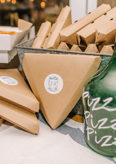 some brown paper bags sitting on top of a table next to a green vase and bottle