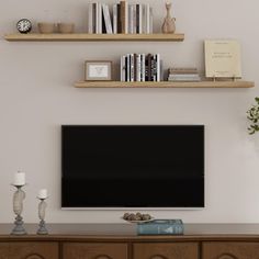 a flat screen tv sitting on top of a wooden dresser next to a book shelf