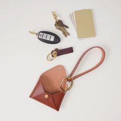 an assortment of keys, wallet and keychain on a white surface