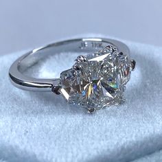 a three stone diamond ring sitting on top of a blanket