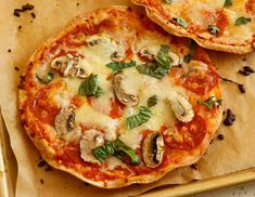 two pizzas sitting on top of a wooden cutting board