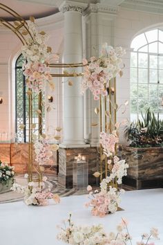 an elegant wedding arch decorated with pink and white flowers in front of a large window