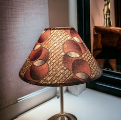 a lamp sitting on top of a table next to a window sill with a mirror in the background