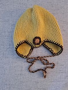 a yellow knitted hat with eye glasses on the side and a brown string attached to it