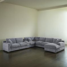 a large gray couch sitting on top of a hard wood floor next to a window