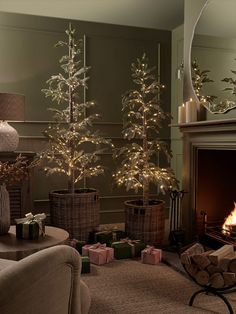 a living room decorated for christmas with small trees and presents on the fireplace mantel