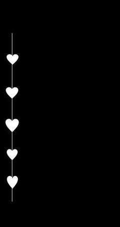 three white hearts hanging from a line on a black background