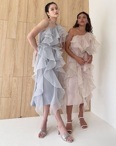 two women standing next to each other in dresses