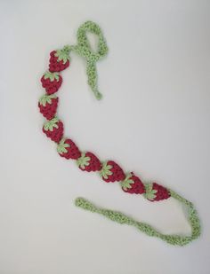 a crocheted red and green headband on a white surface with a pair of scissors next to it