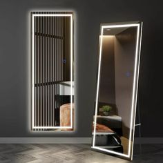 a large mirror sitting on top of a wooden floor next to a wall mounted light