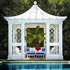 a white gazebo sitting next to a pool with blue and white furniture on it