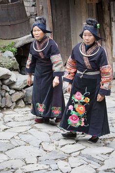 two women in traditional dress walking down a cobblestone street