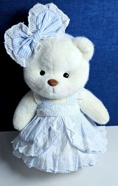 a white teddy bear wearing a blue and white dress