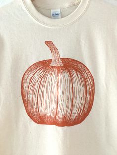 "Hand Printed and Hand Drawn! This is a 100% cotton screen printed t shirt with a hand drawn pumpkin. This shirt is perfect for fall and Halloween! The shirt shown here is Natural and printed in orange ink. // PROCESS: All of our items are individually hand printed by either me or my dad, which can lead to slight variations in placement. The ink is heat cured and will not fade over time. Since our items are printed to order, there is a 1-2 week processing time before shipping. If you absolutely Orange Screen Print T-shirt For Fall, Fall Orange Screen Print Tops, Orange Screen Print Top For Fall, Food Shirt, Fall And Halloween, Pumpkin Shirt, My Dad, Halloween Shirt, Bristol