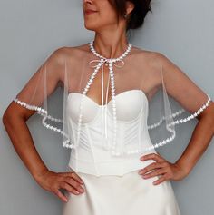 Elevate your bridal look with this enchanting sheer tulle capelet adorned with a whimsical starry trim. This lightweight, mesh bridal topper drapes elegantly over your shoulders, offering a soft, ethereal touch to any wedding gown. Tied gracefully at the neck with delicate satin ribbons, this capelet adds a touch of celestial charm, perfect for modern brides who want to shine. Whether you're seeking a unique wedding shawl, a sheer shrug, or a sophisticated bridal cover-up, this starry-trimmed capelet is the ideal accessory to enhance your special day. Neck perimeter of the model is 13.0" (34 cm). If required larger than this, feel free to contact me. Length: 13.0" (33 cm) For more similar wedding & evening cover-ups, please kindly visit https://www.etsy.com/shop/mammamiabridal?section_id=1 Sheer Capelet, Wedding Dress Capelet, Tulle Bolero, Mesh Wedding Dress, Wedding Dress Cover, Wedding Capelet, Romantic Party, Bridal Capelet, Dress Topper