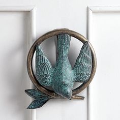 a metal bird mounted to the side of a white door with an open circle around it