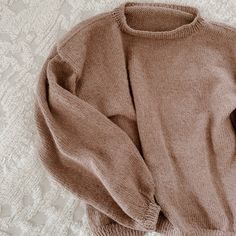 a brown sweater laying on top of a bed