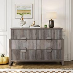 a wooden dresser sitting in a living room next to a lamp and painting on the wall