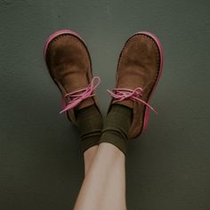 a woman's feet wearing brown shoes with pink laces and green socks on