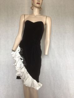 "Vtg 80s Black Velvet Cocktail, NYE Formal Party Dress with white ruffle Dave & Johnny S Preowned. Condition 8/10.  I marked this as so because there is faint reddish hues evident in daylight under the arms.  This is the colour underneath the black dye and occurs with contact with oil, perfume, etc.  at nighttime the reddish hue is not evident. Style A black velvet vixen rock chick evening dress.  Asymmetrical line with the hem lined with a white ruffle edged with memory wire, and a beaded sequinned edge piece adding stark contrast to the inky black velvet. The dress is fully lined  It fastens with a long rear centre zip. The bodice is boned at the side seams and the bra cups. Make an entrance and exit in this number Labelled 7/8 in USA sizing. The dress fits a 10 Australian  Go by measure Formal Fitted Vintage Dress With Ruffles, White Vintage Dress With Ruffles For Evening, Fitted Vintage Dress With Ruffles For Formal Occasions, White Ruffled Vintage Evening Dress, Sleeveless Ruffled Vintage Dress For Evening, Retro Vintage Evening Dress With Ruffles, Vintage Party Dress With Ruffle Hem, Retro Vintage Dress With Ruffles For Formal Occasions, Retro Vintage Dress With Ruffles For Evening