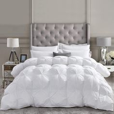 a bed with white comforters and pillows