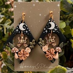 the earrings are decorated with flowers, mushrooms and crescent moon shapes on black acrylic