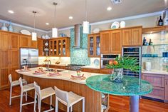 a large kitchen with wooden cabinets and marble counter tops, along with an island in the middle