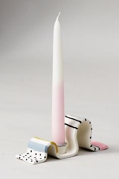 a white candle sitting on top of a table next to two pieces of paper and a brush