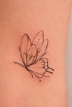 a small butterfly tattoo on the side of a woman's rib - up stomach