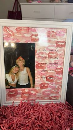 two women are posing in front of a pink photo frame with words written on it