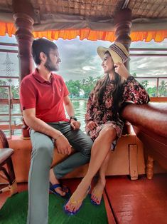 a man and woman sitting on the back of a boat talking while looking at each other