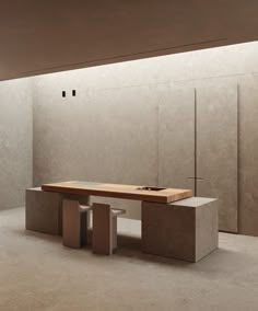 an empty room with a bench and two stools in front of the wall that is made out of concrete