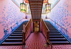 the stairs are painted with blue and pink designs on them, along with chandeliers hanging from the ceiling