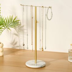 there is a jewelry stand with many necklaces on it and a potted plant in the background