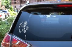 a car with a flower sticker on it's rear window is parked in the street