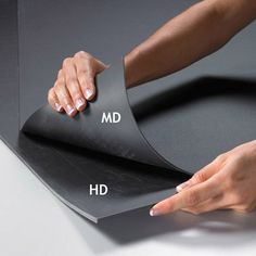 a woman is holding the edge of a black sheet with her hand on it and pointing at it