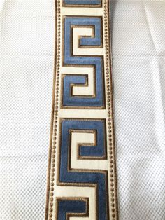 a close up of a neck tie on a white shirt with blue and gold designs