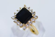 a gold ring with a black stone surrounded by white and clear stones