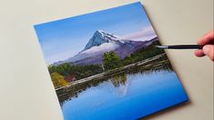 a painting of a mountain is being displayed on a table with a marker in it