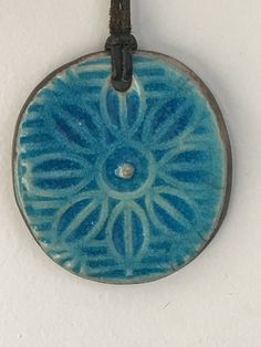 "This lovely necklace has an oval ceramic pendant in a vibrant turquoise shade of blue featuring a flower. The leather cord which is 24\" long is adjustable. The pendant is 2\" long and 1 3/4\" wide. It has initials which I am unable to decipher on its back. It is in overall wonderful preloved condition. Please see all photos for details, as well as, condition. Thank you for looking!" Artisan Blue Medallion Necklace, Adjustable Blue Medallion Necklace, Adjustable Oval Blue Necklace, Adjustable Oval Blue Necklaces, Blue Adjustable Oval Necklaces, Adjustable Blue Flower Pendant Necklace, Blue Necklace With Adjustable Cord As Gift, Blue Adjustable Cord Necklace For Gift, Hand Painted Blue Adjustable Necklaces