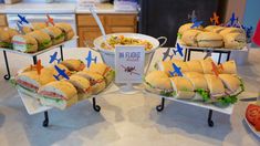 sandwiches and salads are displayed on trays at a party or gathering in the kitchen