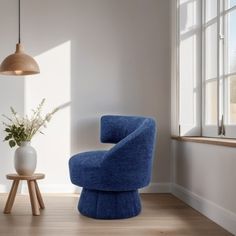 a blue chair sitting in front of a window next to a vase with flowers on it