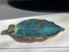 a blue leaf shaped dish sitting on top of a white cloth covered table next to a car